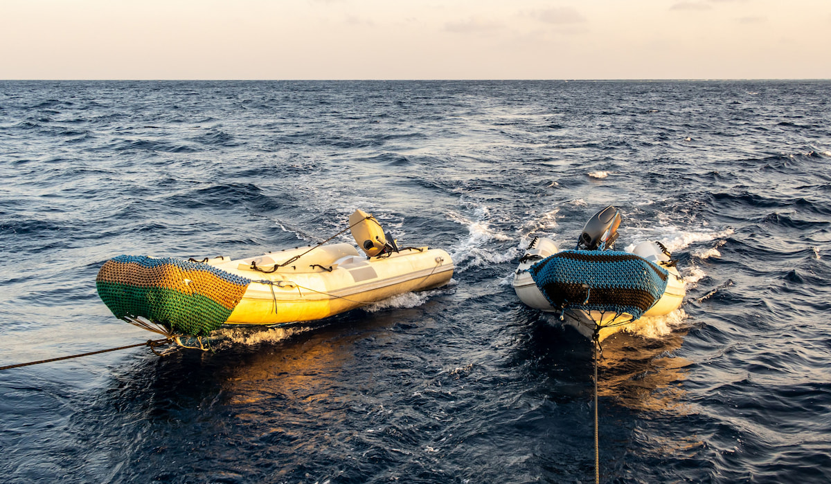 Two big fast empty dinghy being towed by a diving motor boat