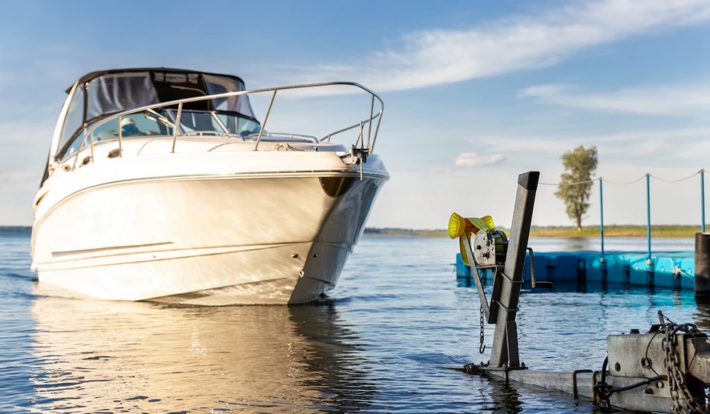 Big luxury cabin motorboat cruiser yacht launching at trailer ramp on river 