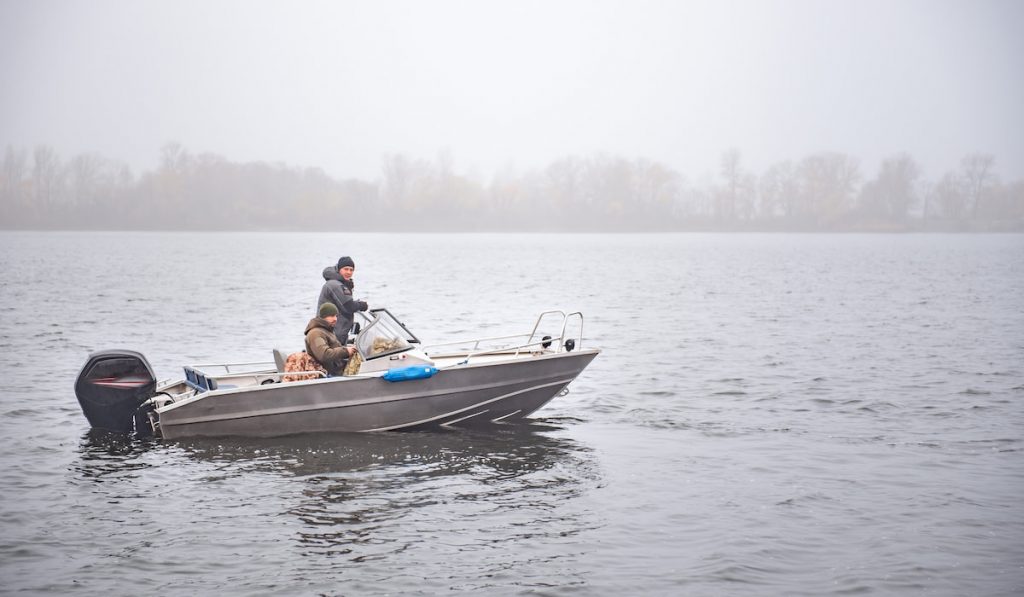 Fishermen on the motorboat on the autumn river