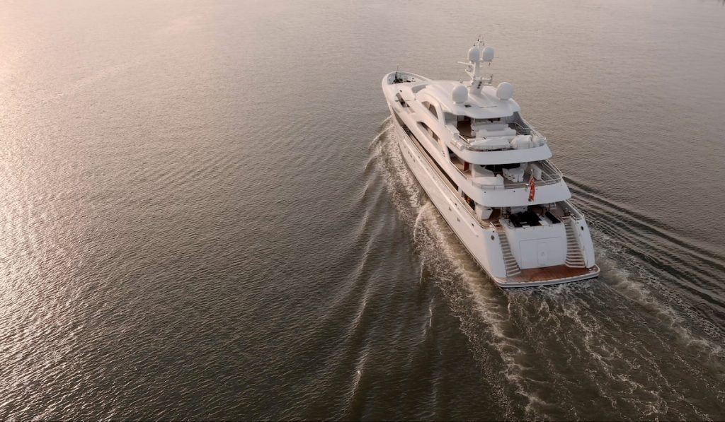 Low aerial view of large mega yacht crossing the ocean at sunrise.
