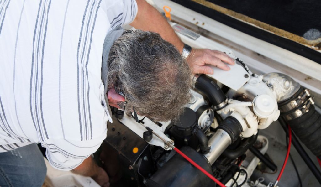 man checking on a boat engine